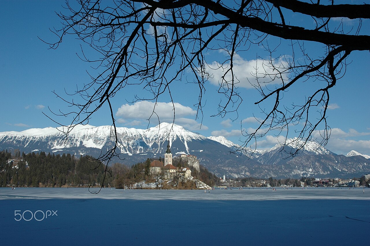 Lake Bled frozen in winter with snow around the island church